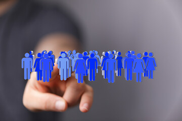Image depicting a hand interacting with a digital representation of a diverse crowd.