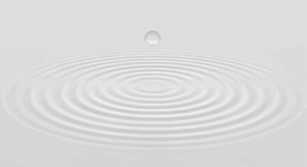 A single droplet suspended above a white surface, creating concentric ripples in the liquid below.
