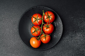 Fresh, ripe tomatoes displayed on a black plate against a dark background