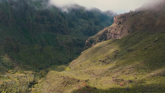 Aerial view of lush green cliffs near Masca with sun rays breaking through clouds, Tenerife, Canary Islands