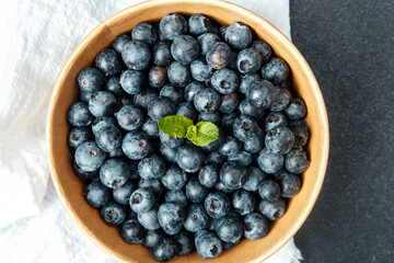 Fresh blueberries in a wooden bowl on a dark countertop