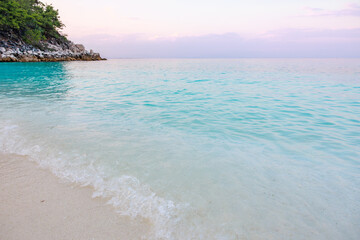 A beautiful beach with a calm ocean and a rocky shore