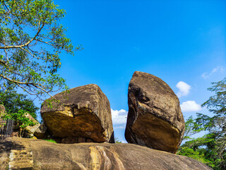 Split boulder formation under a bright blue sky