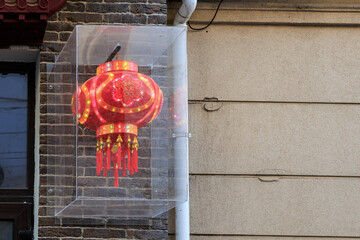 Red chinese lantern on brick wall with glowing lights in urban setting