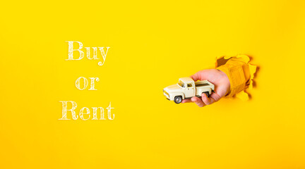 Hand holding a toy truck emerging from a yellow background with text suggesting buy or rent options