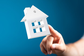 Modern real estate concept. Hand pointing at a 3D house model.  Home buying, selling, or renting.