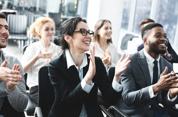 Business lecture. Happy executives applauding to speaker, listening his speech in boardroom