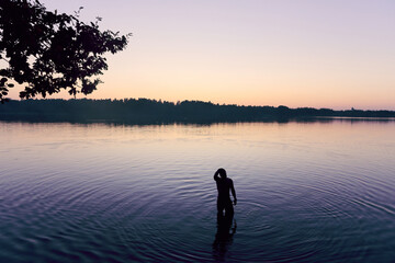 A man stands in a lake at sunset