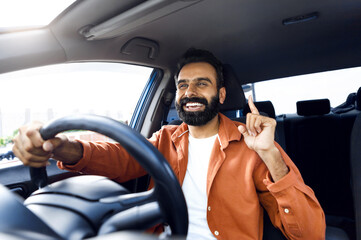 Road Adventure. Cheerful Indian Man Riding Car And Singing Sitting In Front Driver Seat Inside...