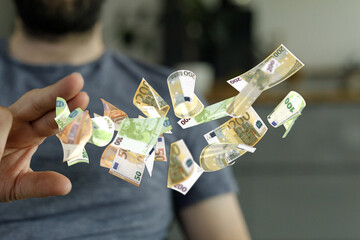 Image of a man releasing flying euro banknotes.  Concept of finance, wealth, or spending.