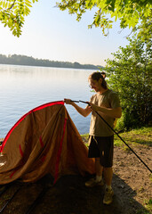 a man builds a tent in nature, camping theme