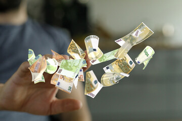 Close-up of a hand catching falling euro banknotes.  Wealth, success, finance concept.