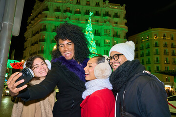 Friends taking selfie in front of christmas lights decoration at night