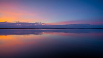 Naklejka premium Reflections of a vibrant sunset on calm lake waters create a serene and picturesque landscape view during dusk or dawn