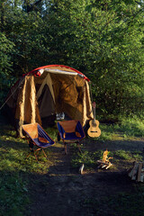a tent with chairs and a burning campfire by the lake