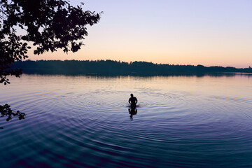 A man stands in a lake at sunset