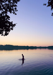 A man stands in a lake at sunset