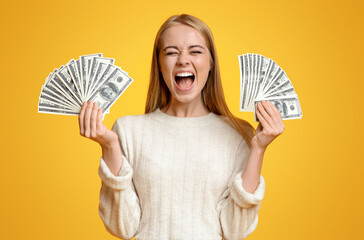 Big prize. Happy teenage girl holding lots of money and shouting, orange background with free space