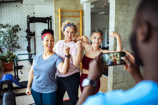 Senior women flexing muscles and posing for photo after gym workout session