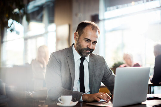 Businessman working remotely on laptop at modern coffee shop