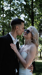 A loving bride and groom pose for the camera during a wedding photo shoot in a park. The man and...