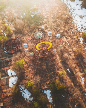Aerial view of a decaying Ferris wheel and overgrown amusement park structures, tinged with the melancholy hues of abandonment, &Aring;&OElig;saki, Miyagi, Japan.