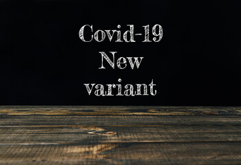 Covid-19 new variant text displayed on a wooden table with dark background for informative purposes