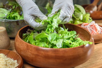 woman chef mix fresh baby cos salad and pour salad dressing in glass blow. Organic Vegetables mix...
