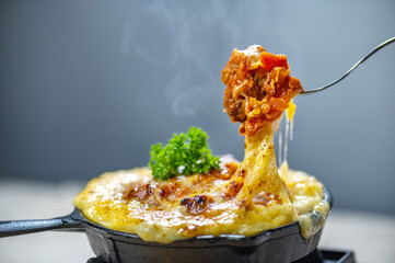 Delicious cheesy baked casserole with melted cheese, ground meat, tomato sauce, garnished with...