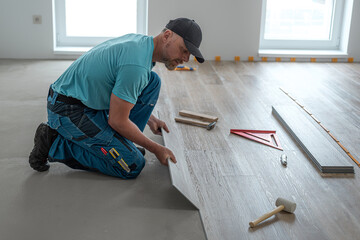 Floating floor work. The worker inserts the board of vinyl plank to the click system of Floating...