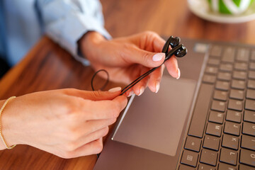 Professional woman wearing wired headphones, working remotely with laptop, demonstrating contemporary digital workplace connectivity
