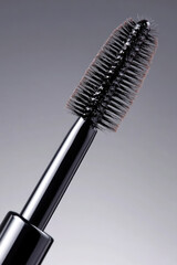 Mascara wand is positioned at an angle, with bristles clearly visible. Makeup accessory, beauty tool, close-up detail
