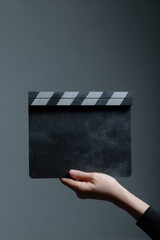 A hand holds a black and white clapperboard, preparing to start a film scene. Concept: filmmaking, cinema, action