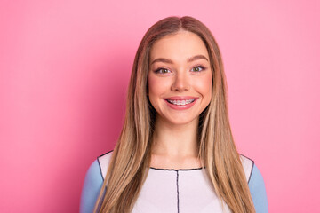 Charming young woman smiles confidently with charming braces against a lively pink backdrop,...
