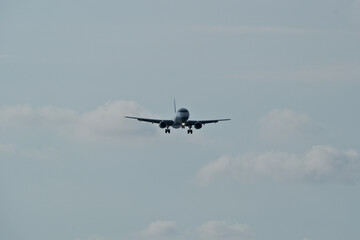 The airplane approaches the airport against a backdrop of clouds. The airplane is ready to land....