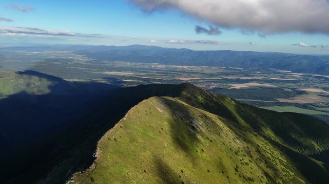 Aerial view of majestic mountains casting shadows on the lush green fields in the distance, Jamn&iacute;k, zilina Region, Slovakia.