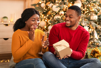 Gifts for new years eve or Christmas together. Millennial happy african american husband gives box...