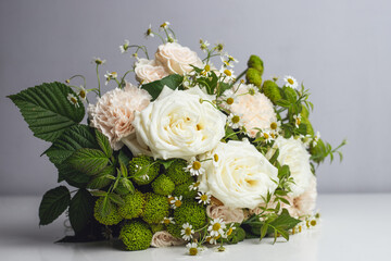 Bouquet of white roses, delicate pink carnations and varietal green carnations with raspberry branches and small daisy buds. Professional floral wedding arrangement on a white background