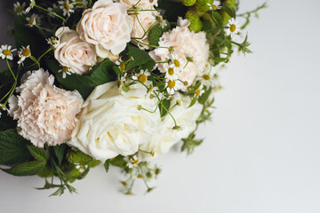 Bouquet of white roses, delicate pink carnations and varietal green carnations with raspberry branches and small daisy buds. Professional floral wedding arrangement on a white background. Top view