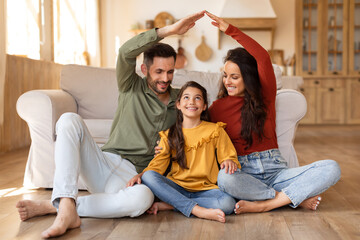 Smiling family creating a heartwarming scene by fashioning a house shape with their hands while...