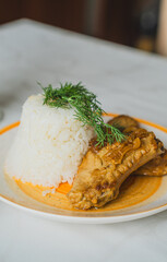 Plate showcases fluffy white rice shaped into a mound beside a piece of tender chicken garnished with fresh herbs perfect for a satisfying meal