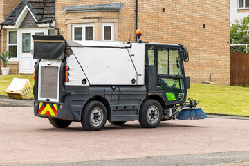 Street sweeper cleaning residential road in suburban neighborhood