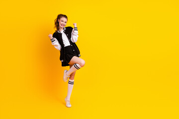 Young female student in stylish sportswear on yellow background expressing positivity and...