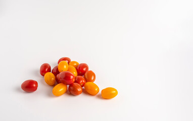Scattered red and yellow cherry tomatoes on white background, fresh and colorful.
