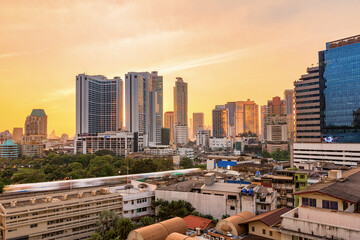 Bangkok business district with the public park area in the foreground at sunset time.