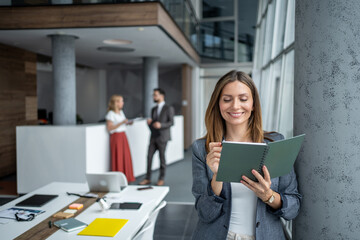 Smiling businesswoman reading notes in modern office lobby