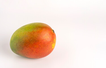 Whole mango with green, yellow, and red skin on clean studio backdrop
