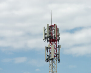 Close-up photo of a Telecommunications tower, painted in a distinctive red and white pattern with a...