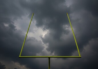 A football goalpost stands against a dramatic, stormy sky
