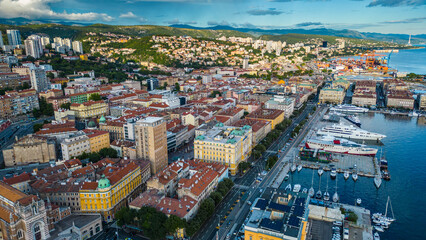 Fototapeta premium Rijeka city center and waterfront aerial view at sunset, panoramic view of the Kvarner Gulf in Croatia. Scenic harbor with boats, historic architecture, container terminal, canals, seafront promenade